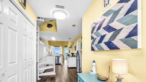 A hallway with white doors, a blue dresser, a lamp, and a painting on the wall.