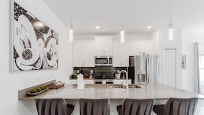 A modern kitchen with white cabinets, stainless steel appliances, and a central island with bar stools.