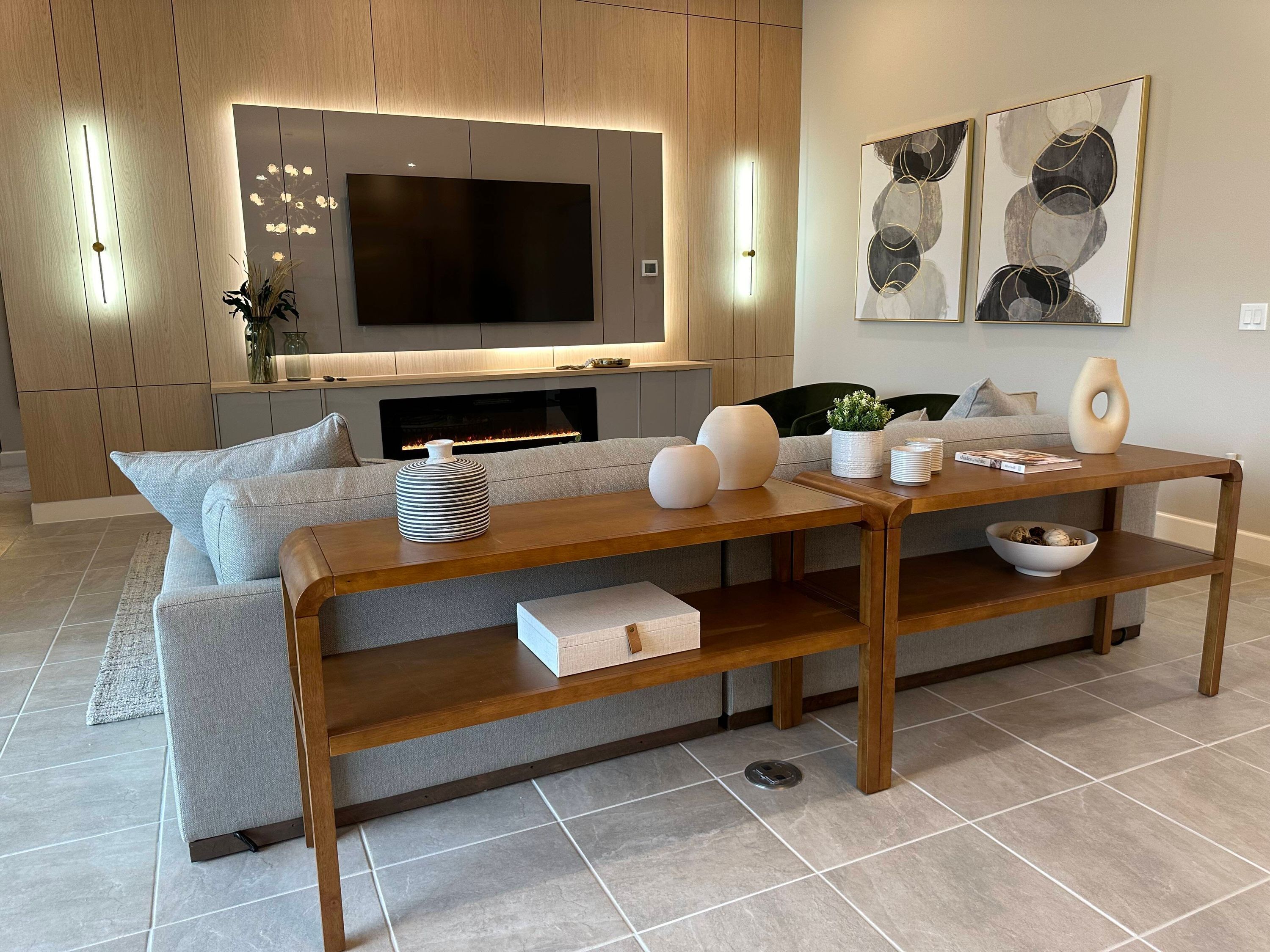 A modern living room with a sofa, a wooden coffee table, and a flat-screen TV mounted above a fireplace.
