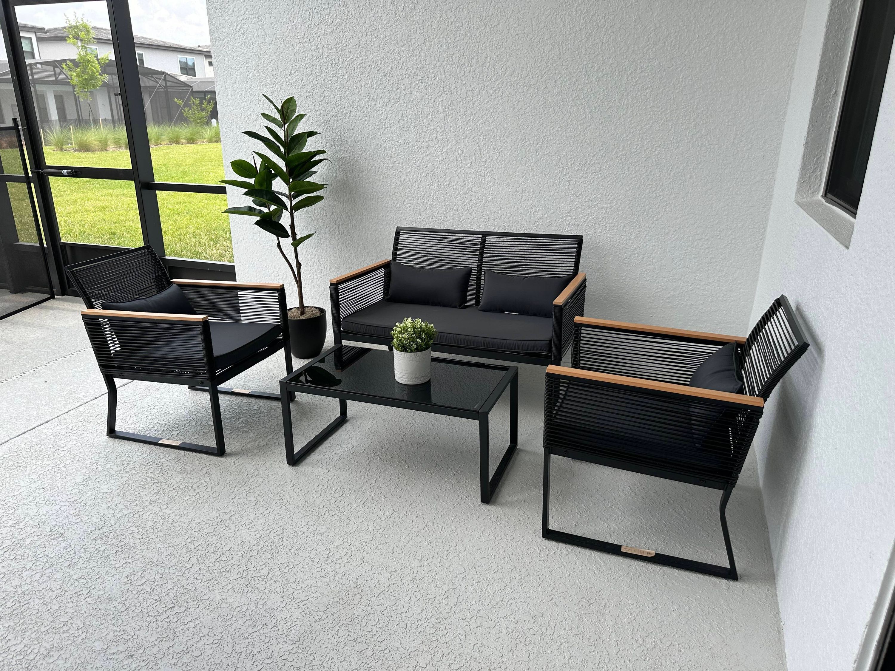 Een moderne zithoek buiten, met een bank, twee stoelen en een bijzettafeltje.