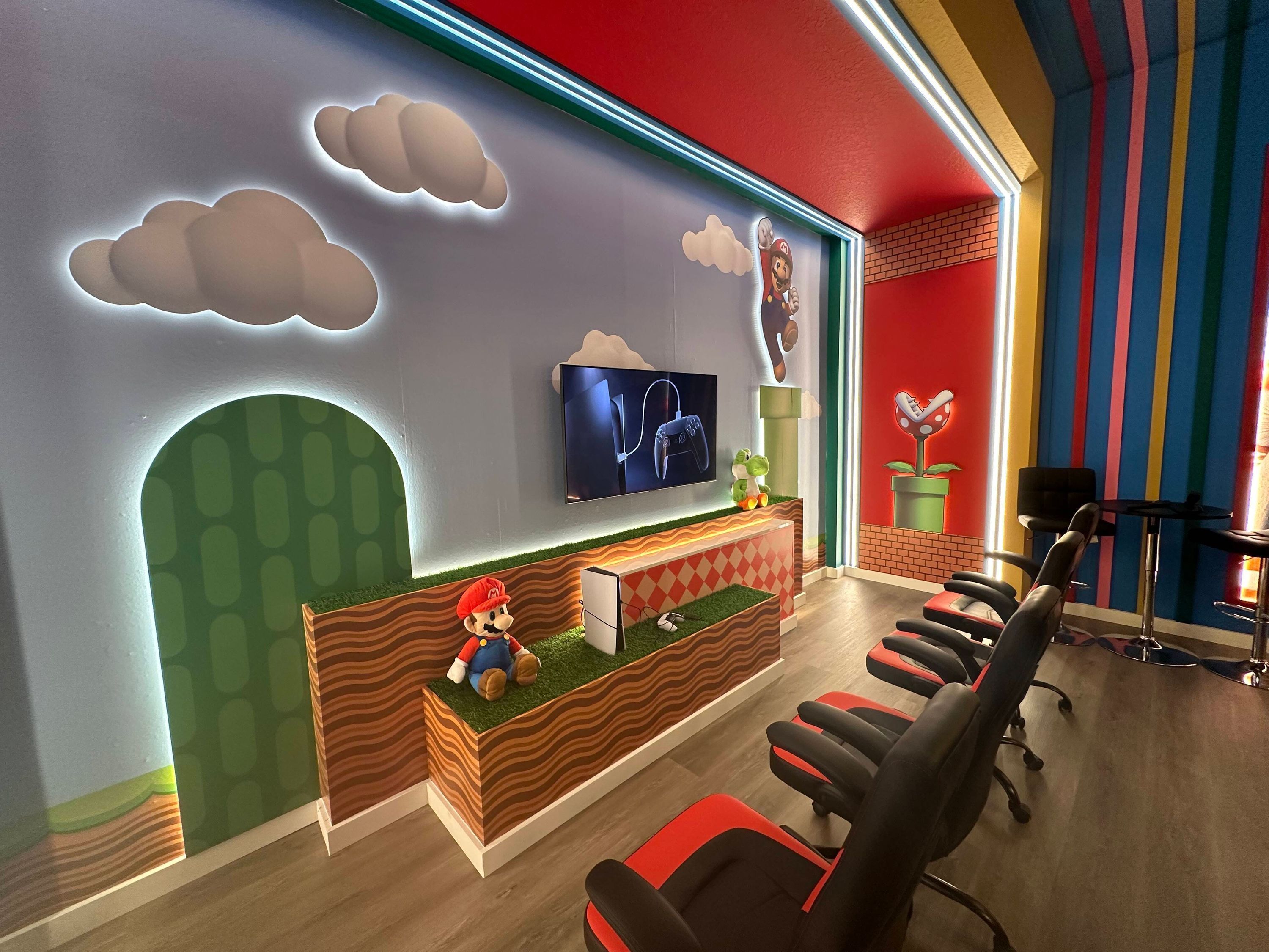 A Mario-themed reception area with a TV, plush toys, and a colorful striped wall.