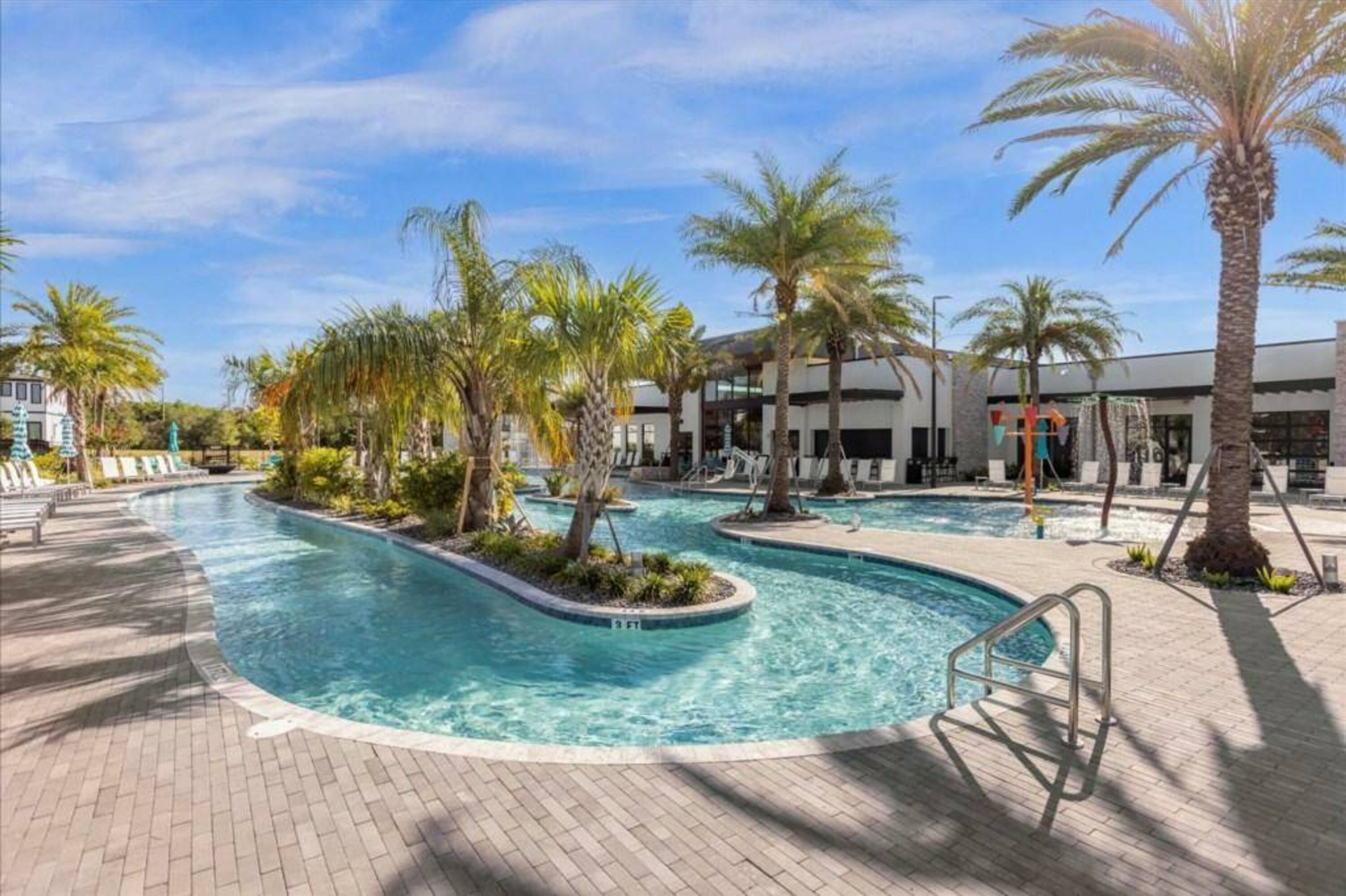 A swimming pool with palm trees and a brick pathway.
