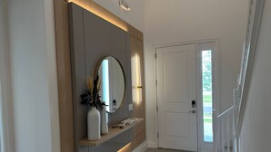 A modern hallway with a built-in bench, a large mirror, and a door leading outside.