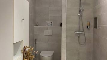 A modern bathroom with a shower, toilet, and a towel rack.