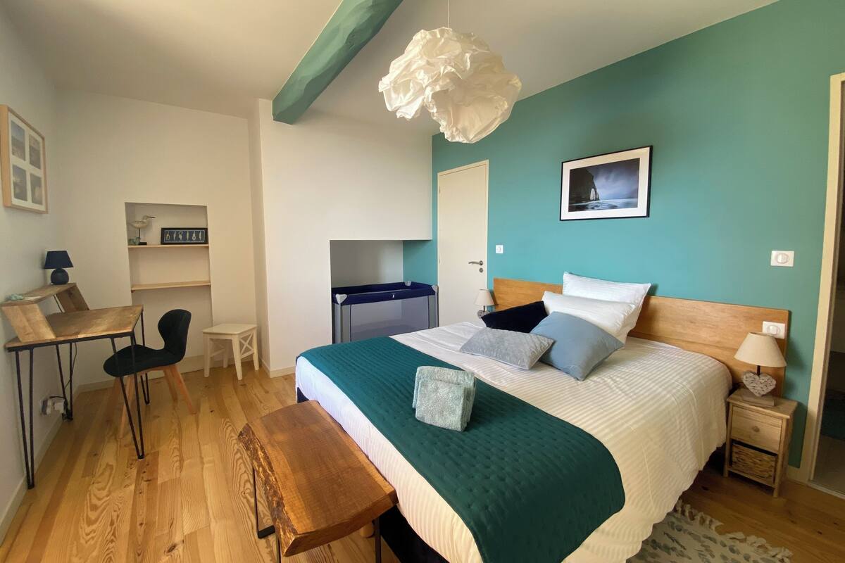 Ein Schlafzimmer mit Bett, Nachttisch, Lampe und Schreibtisch mit Stuhl.