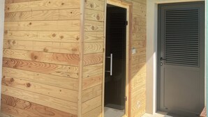Eine Holzhütte mit Glastür, Metalleingang und einem begrünten Dach mit Beleuchtung.