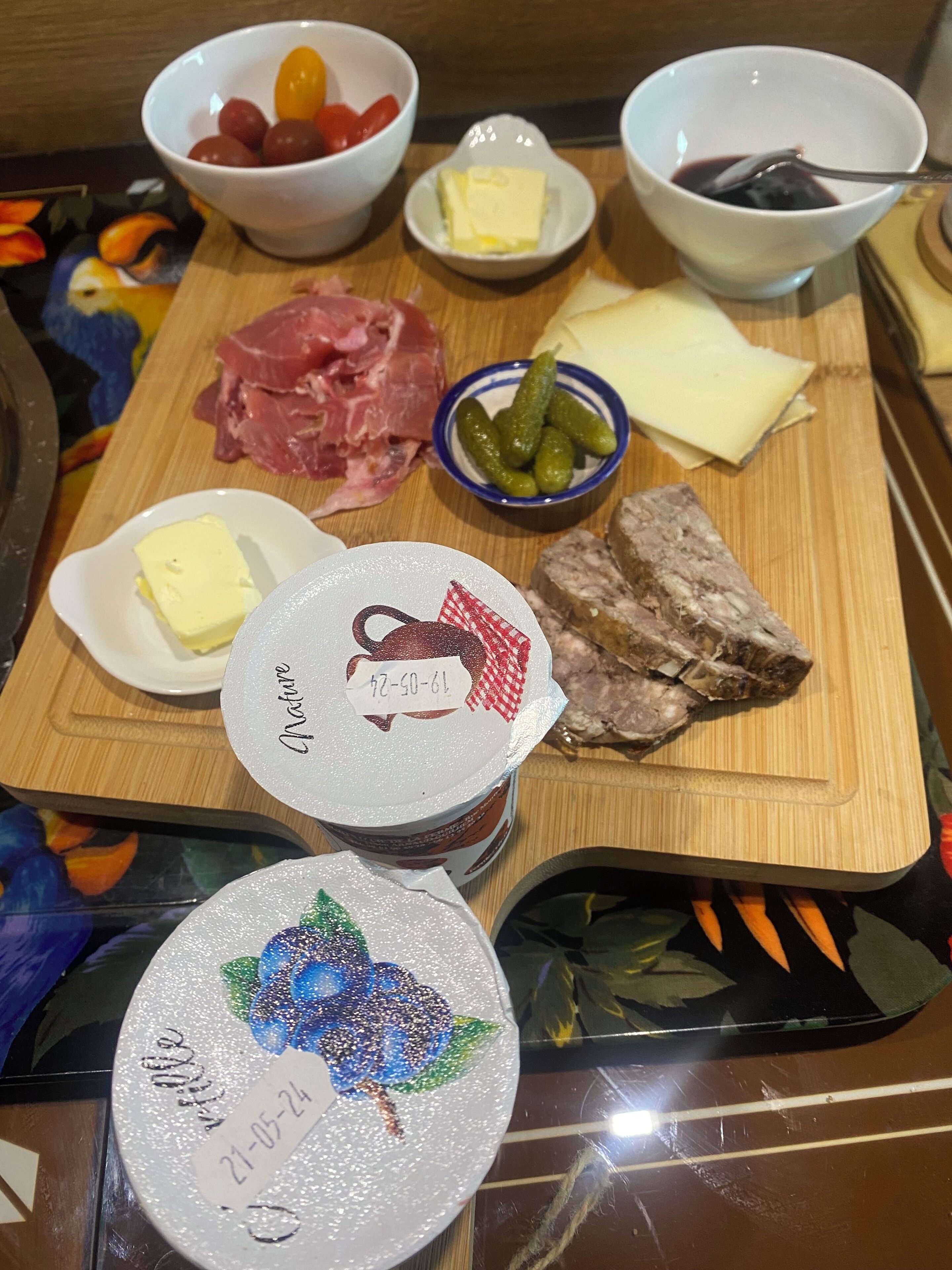 Una tabla de madera con diversos alimentos, entre ellos carnes, quesos y encurtidos.