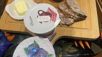 Una tabla de madera con diversos alimentos, entre ellos carnes, quesos y encurtidos.