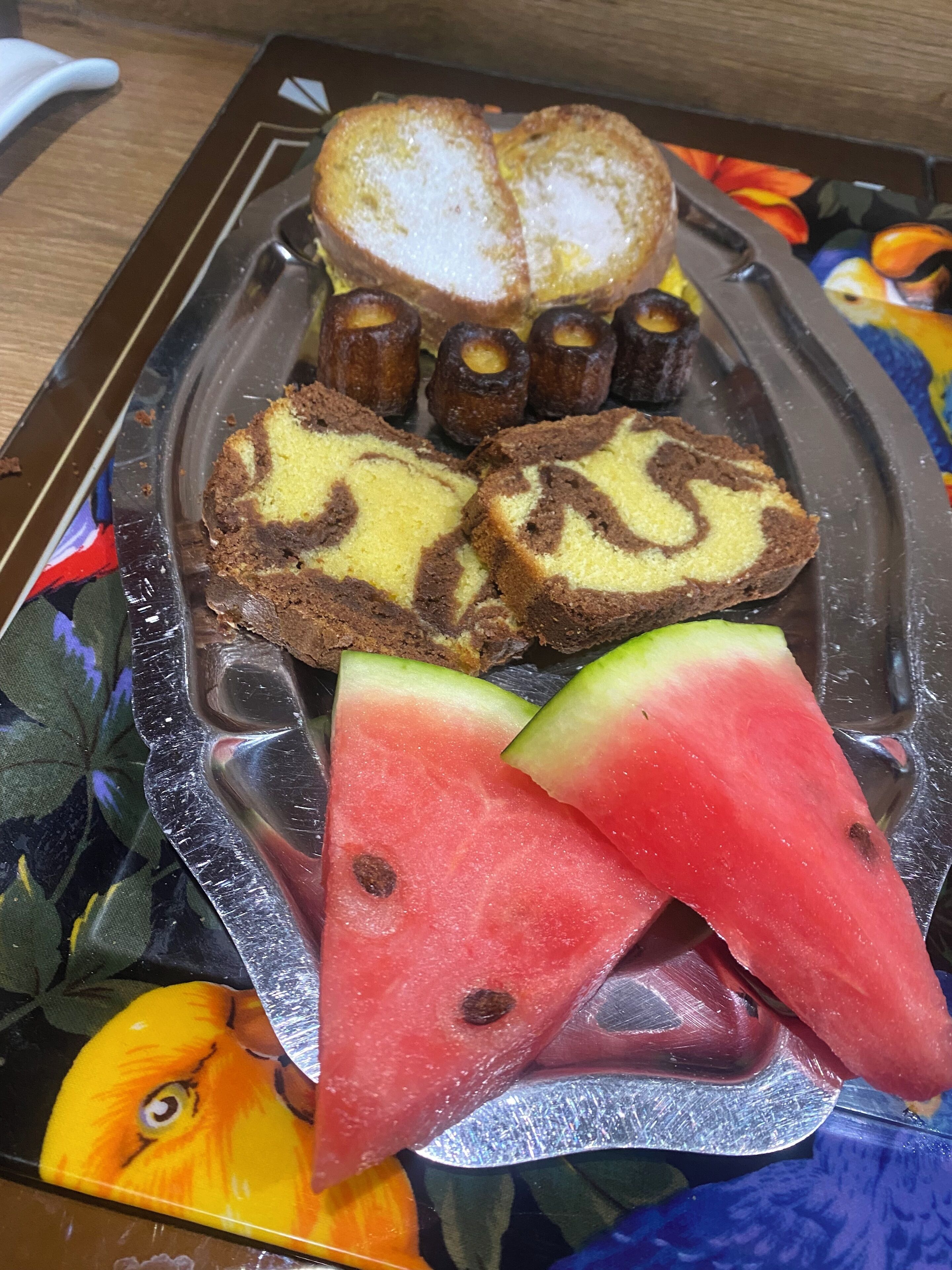 A tray with slices of cake, a loaf, and watermelon pieces.