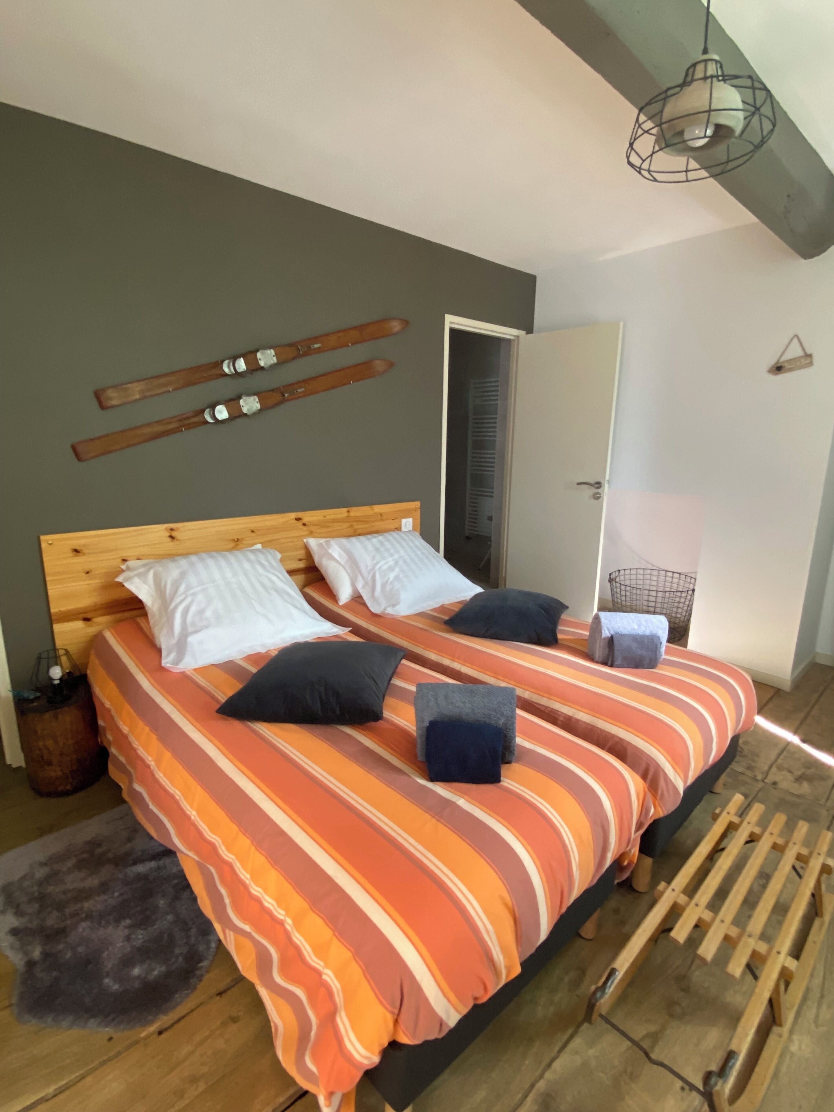 Un dormitorio con cama de madera, ropa de cama a rayas y una lámpara colgante.