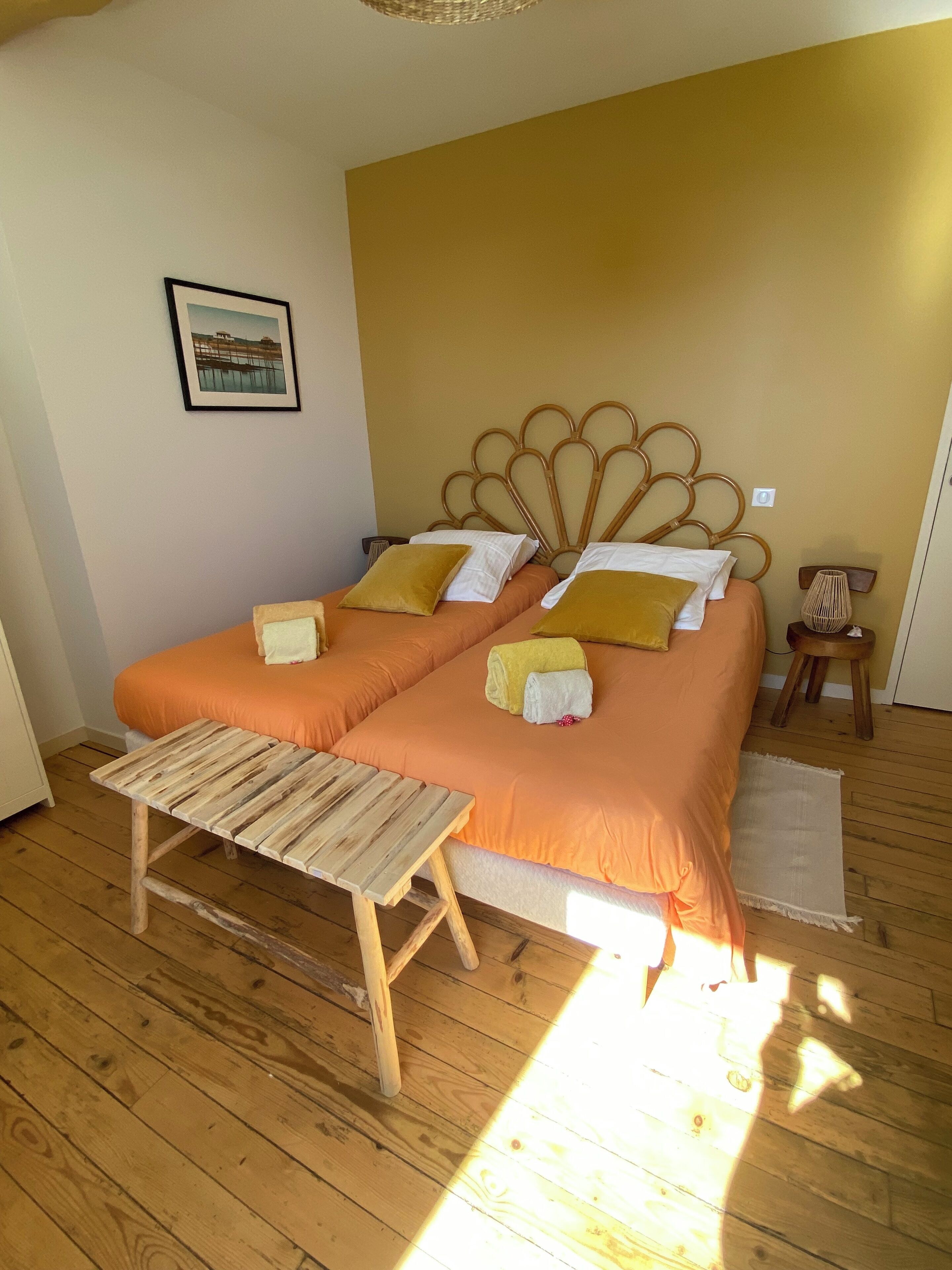 Una cama doble con cabecera de madera, una mesita de madera y un cuadro en la pared.