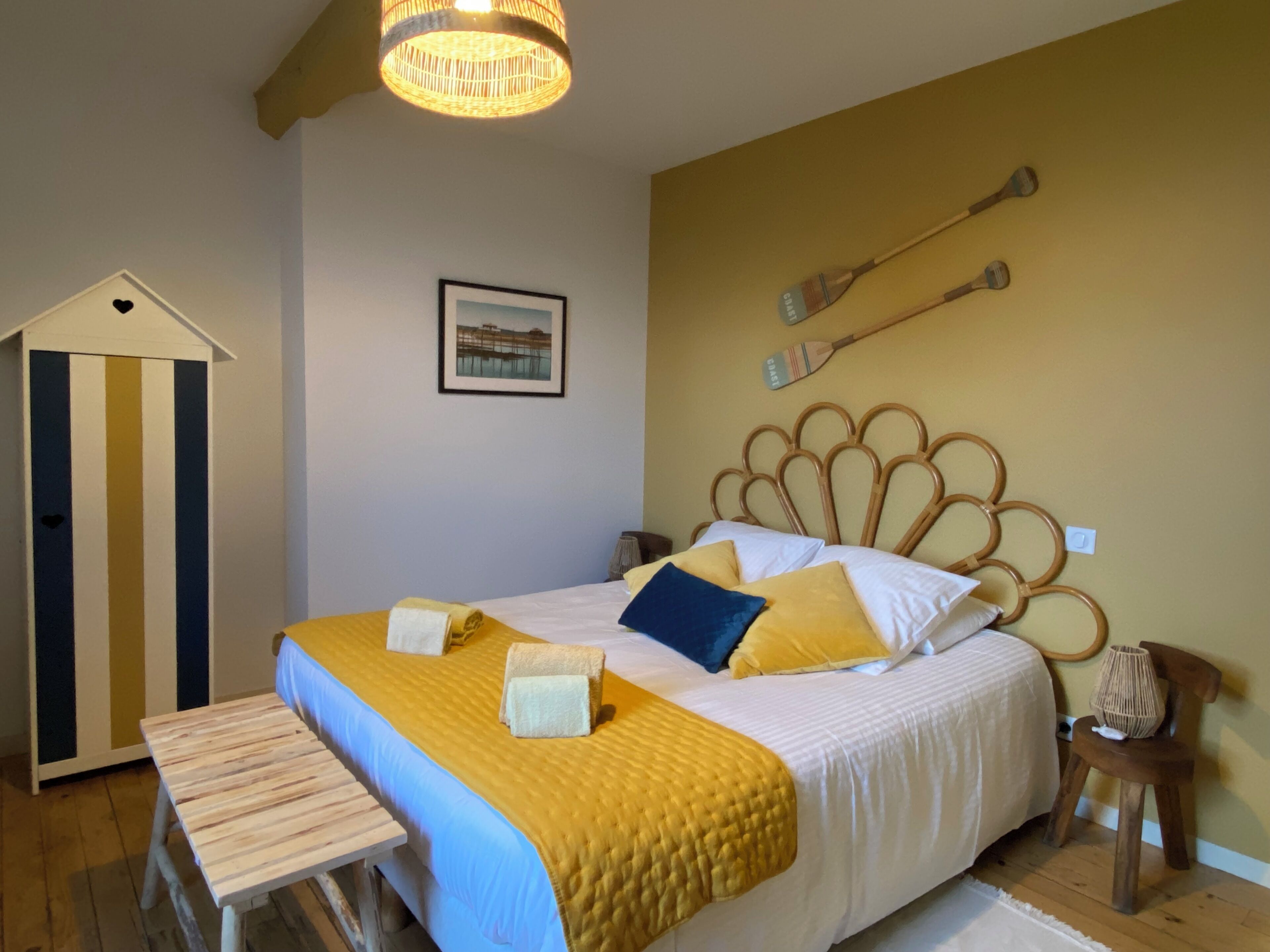 Un dormitorio con cama, un banco de madera, un cuadro en la pared y un diseño de cabecera único.