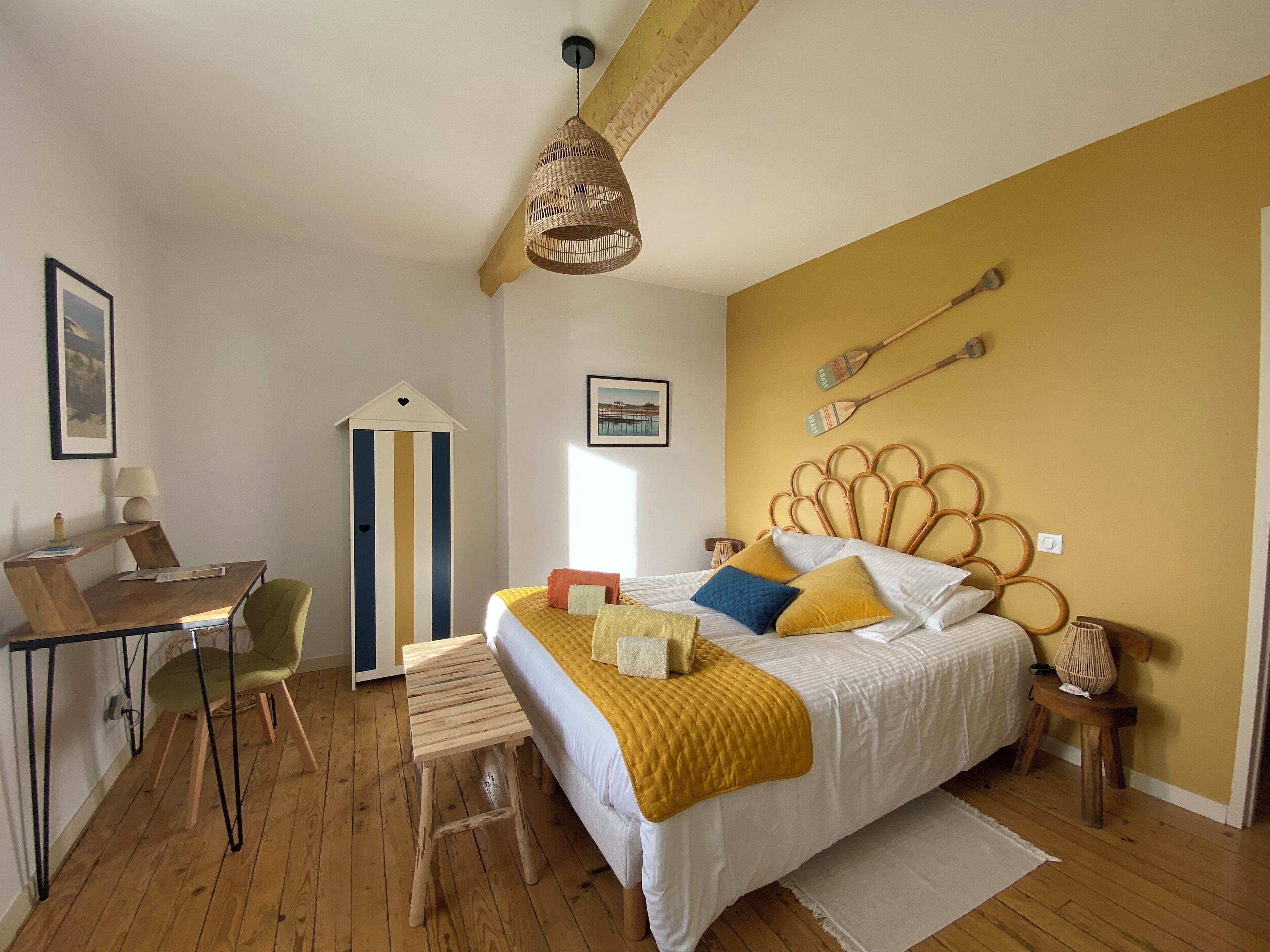 A bedroom with a bed, a desk, a chair, a lamp, and a hanging light fixture.
