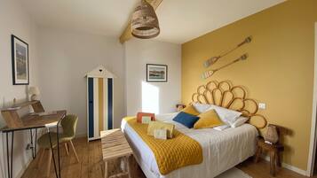 A bedroom with a bed, a desk, a chair, a lamp, and a hanging light fixture.