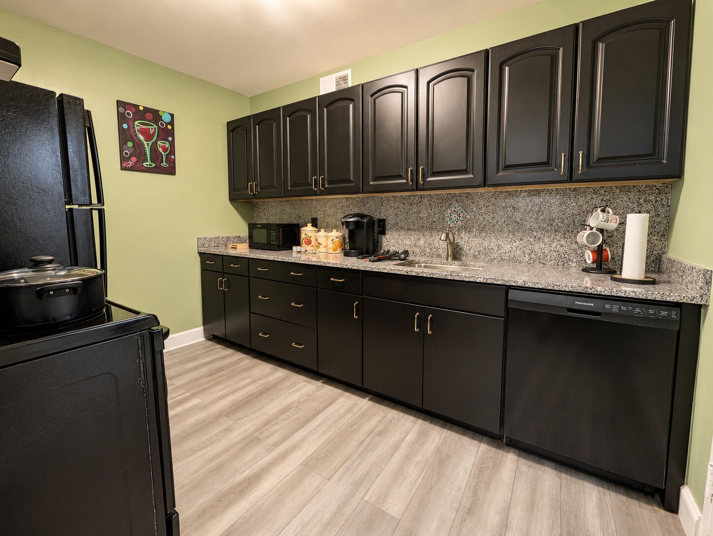 A kitchen with dark cabinets, a microwave, a coffee maker, and a dishwashing unit.
