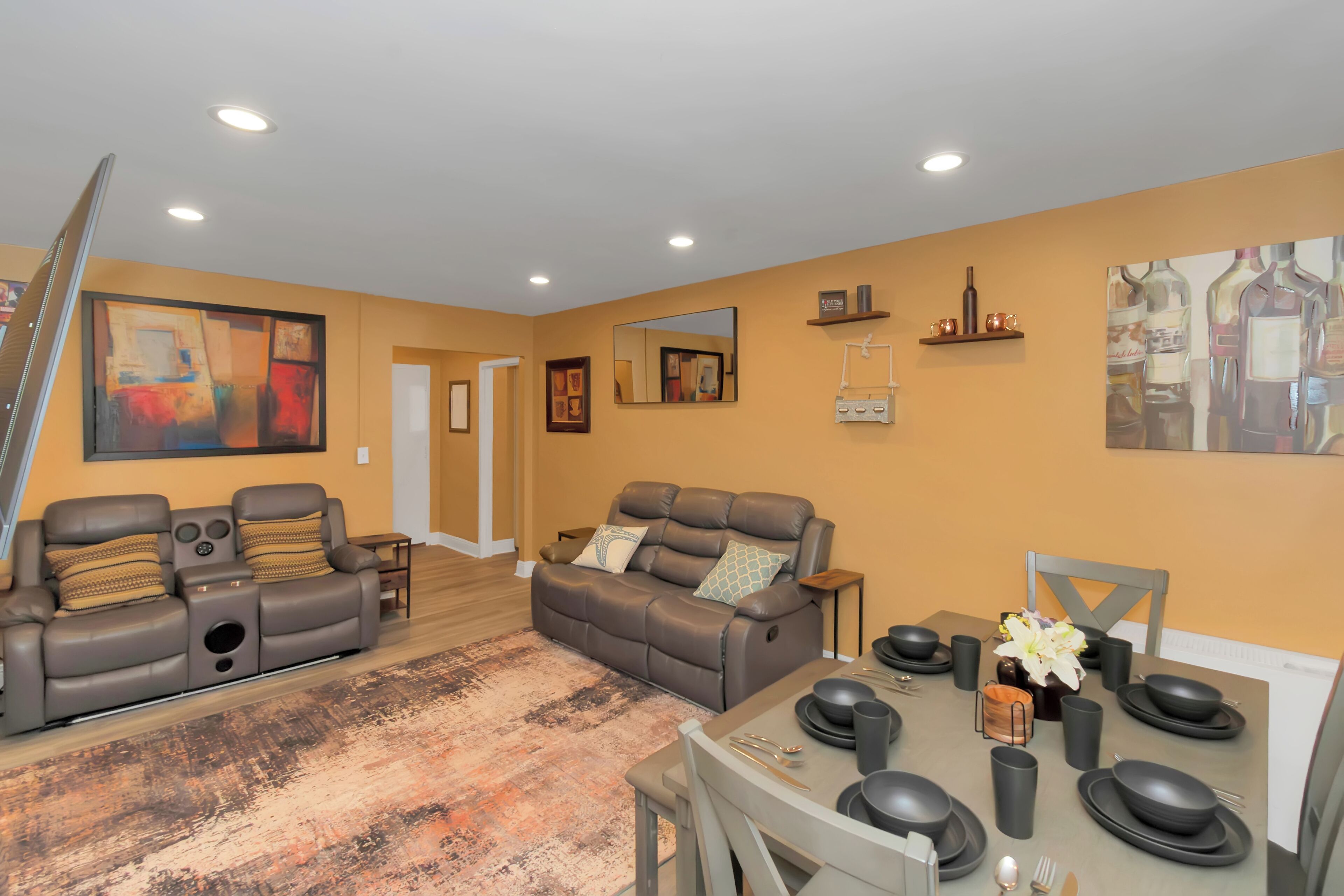 A spacious living room with two sofas, a dining table set for four, and a staircase leading to another room.