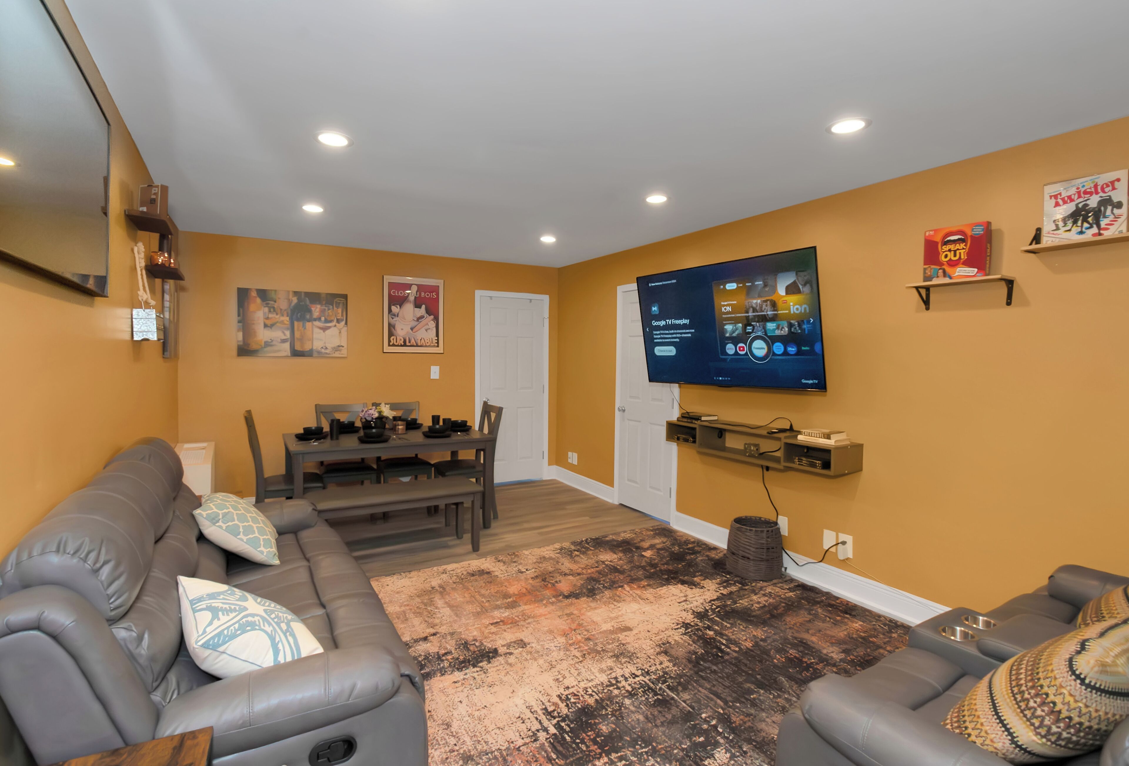 A living room with a gray sofa, a coffee table, and a TV mounted on the wall.