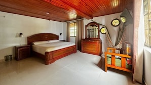 A bedroom with a wooden ceiling, a bed, a dresser, and a mirror.