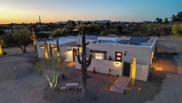 Un bâtiment moderne doté d’un toit plat, entouré de cactus et de plantes du désert.