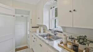 A kitchen with white cabinetry, a double sink, and a window.