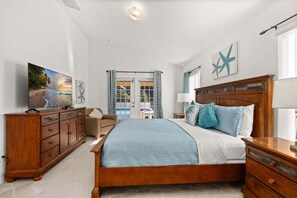 A bedroom with a wooden bed, a dresser, a nightstand, a lamp, and a painting of a beach scene.