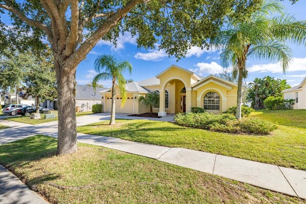 A residential house with a front yard, driveway, and a palm tree.