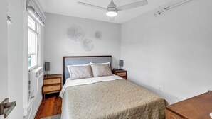 A bedroom with a bed, a ceiling fan, a nightstand, and a wall-mounted lamp. - Ocean Grove Renovated 1BR 2 Blocks to Beach & Main Ave | Near Asbury Boardwalk (Neptune Township)