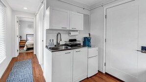 A compact kitchen with white cabinets, a sink, and a coffee machine. - Ocean Grove Renovated 1BR 2 Blocks to Beach & Main Ave | Near Asbury Boardwalk (Neptune Township)