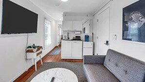 A modern living room with a grey sofa, a white coffee table, and a flat-screen TV mounted on the wall. - Ocean Grove Renovated 1BR 2 Blocks to Beach & Main Ave | Near Asbury Boardwalk (Neptune Township)