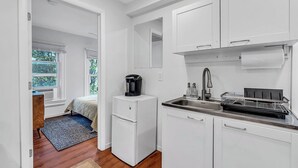 A compact kitchen with white cabinets, a sink, and a coffee maker.