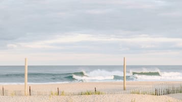 A beach with a wooden fence and two poles, leading to the ocean.