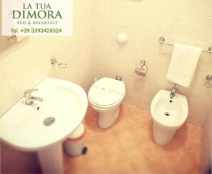 A small bathroom with a sink, toilet, and bidet. - B&B LA TUA DIMORA (Palermo)