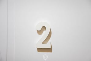 Un mur blanc orné d’un grand chiffre « 2 » en relief.