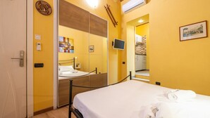 Een hotelkamer met een bed, een spiegel, een televisie en een houten kledingkast.