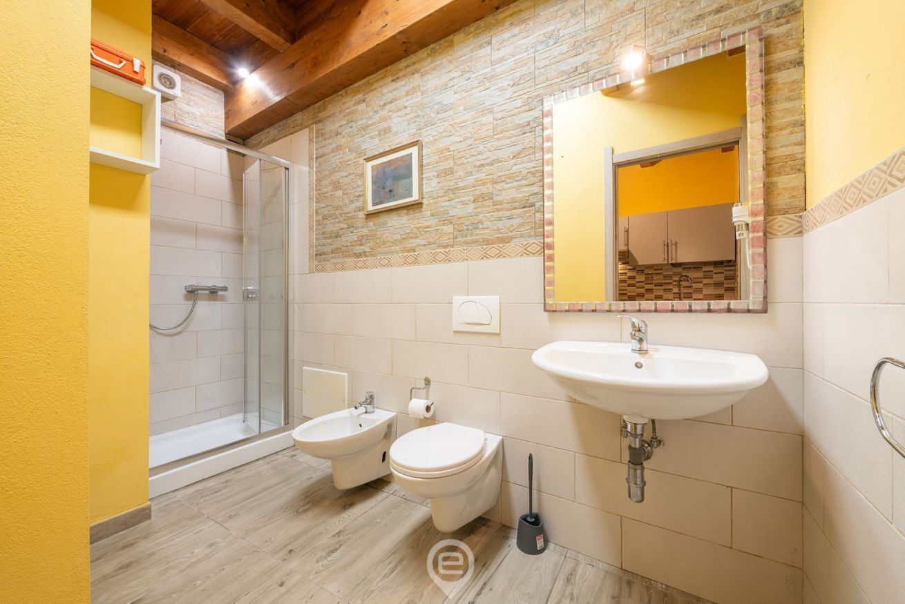 A bathroom with a shower, bidet, toilet, and sink.