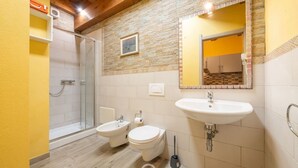 Een badkamer met een douche, wc, wastafel en bidet.