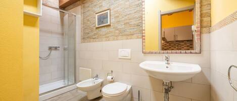 A bathroom with a shower, bidet, toilet, and sink.