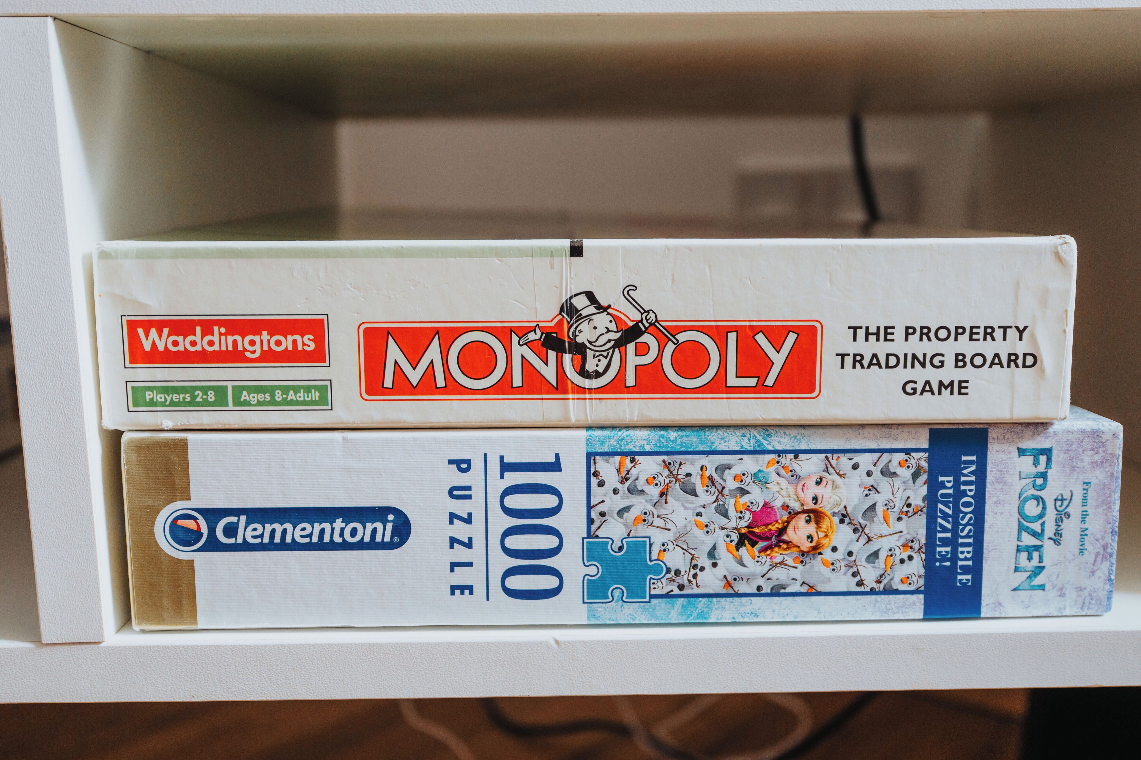 Une étagère avec deux jeux de société : Monopoly et un jeu de puzzle.