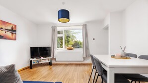 Een moderne woonkamer met een televisie, bank en eettafel.