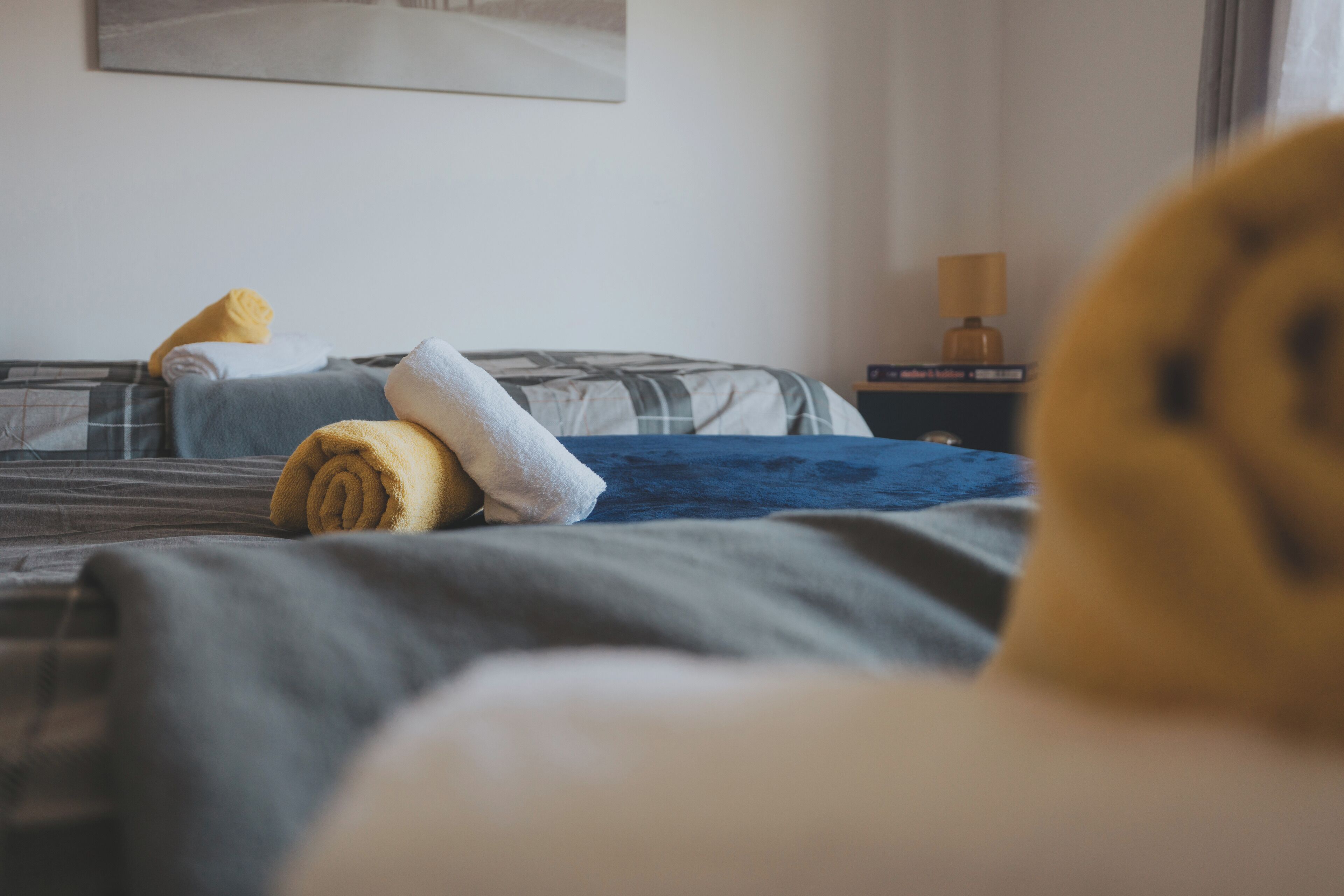 Een hotelkamer met een bed, kussens en een nachtkastje met een lamp.