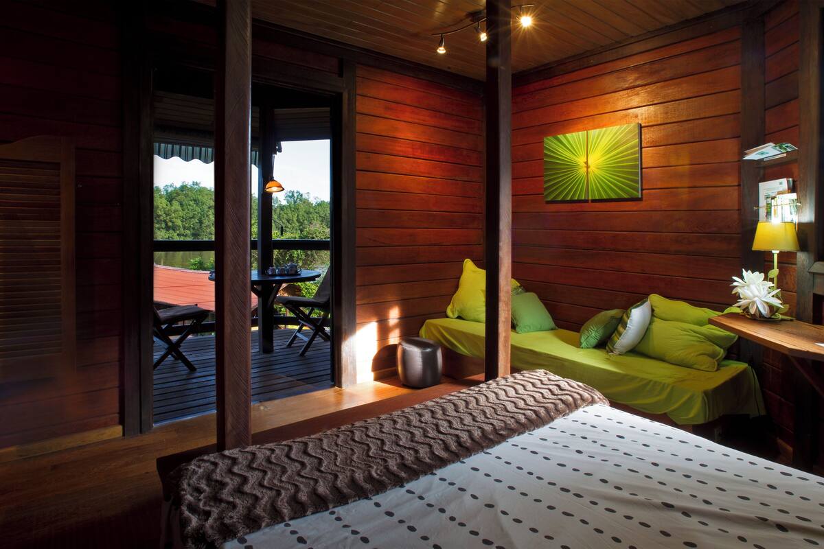 Une chambre dans une cabane en bois, avec un lit, un canapé vert et une table à manger.