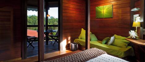 Un dormitorio de cabaña de madera con una cama, un sofá verde y una mesa de comedor.