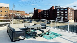A rooftop patio with outdoor furniture, a view of the cityscape, and a clear sky. - Spacious and luxurious downtown loft in Logansport w/ incredible rooftop patio (Logansport)