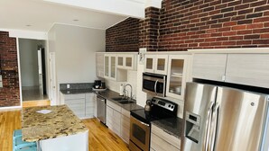 A modern kitchen with stainless steel appliances, light wood cabinets, and a granite countertop. - Spacious and luxurious downtown loft in Logansport w/ incredible rooftop patio (Logansport)