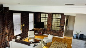 A spacious living area with a fireplace, a flat-screen TV, and a kitchen area with a countertop and cabinets. - Spacious and luxurious downtown loft in Logansport w/ incredible rooftop patio (Logansport)