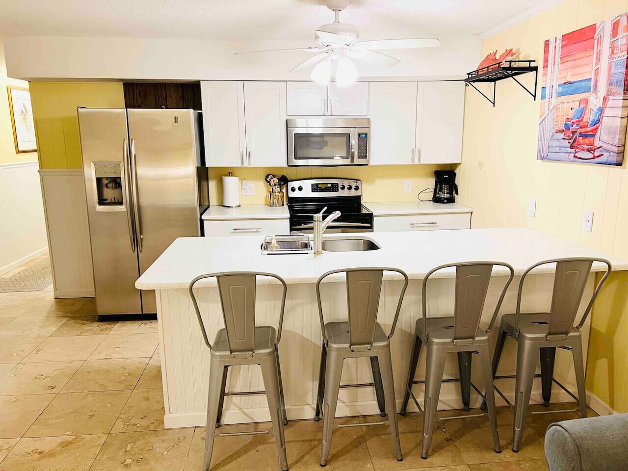 A kitchen with a central island, stainless steel appliances, and a ceiling fan.
