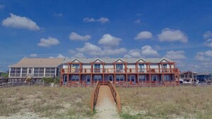 Een strandhotel met een houten terras en een overdekte doorgang naar de ingang.