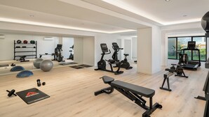 A modern home gym with exercise equipment, a bench, and a mirror. - With pool in Funchal - Acqua Residence V (Funchal)