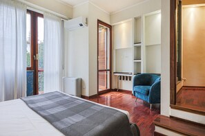 Una habitació d'hotel amb llit, escriptori, cadira i vistes a l'exterior.