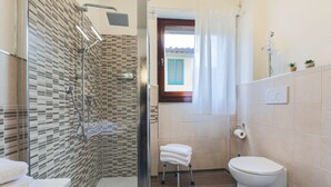 Une salle de bain avec une douche, des toilettes et un petit tabouret.
